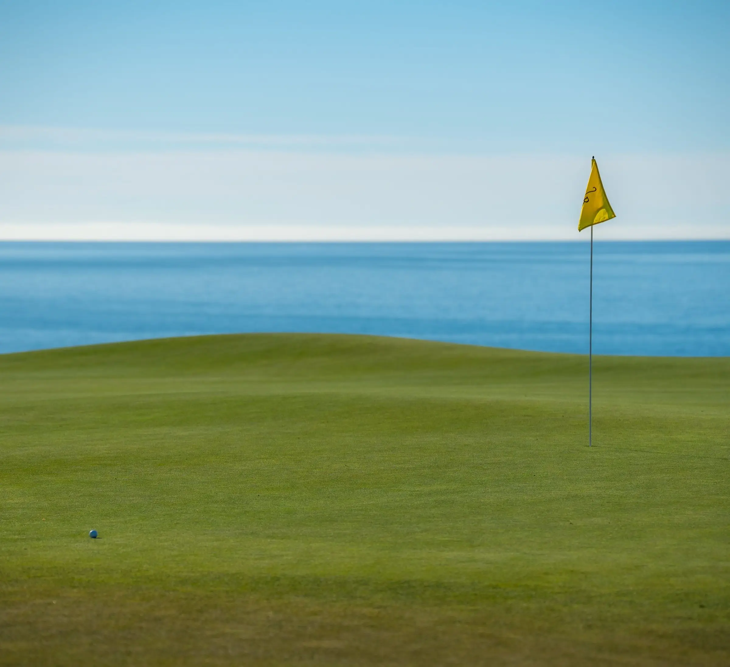 Golfgrün mit Fahne direkt am Meer